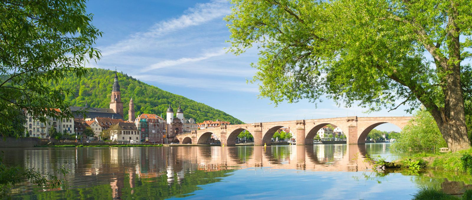 Alte Brücke und Altstadt von Heidelberg am Neckar, im Hintergrund bewaldete Hügel